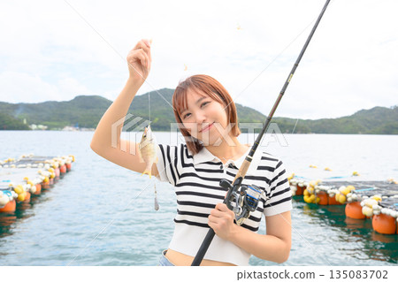 A woman smiling as she shows off the fish she caught. (Photo courtesy of Oki Seaside Resort Miyabi) 135083702