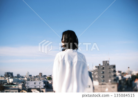 一位女子站在屋頂上的背影 一位女子站在屋頂上的背影 135084515
