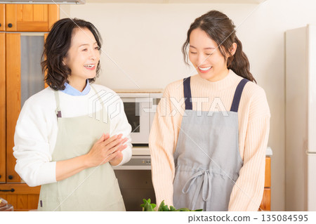 Daughter learning cooking from mother Daughter learning cooking from mother 135084595