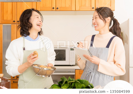 Daughter learning cooking from mother Daughter learning cooking from mother 135084599
