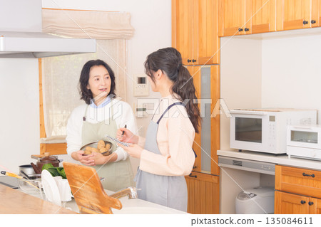 Daughter learning cooking from mother Daughter learning cooking from mother 135084611