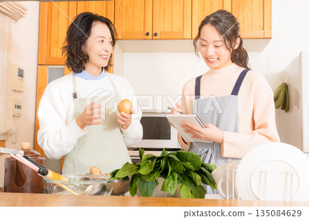 Daughter learning cooking from mother Daughter learning cooking from mother 135084629