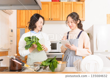 Daughter learning cooking from mother Daughter learning cooking from mother 135084632