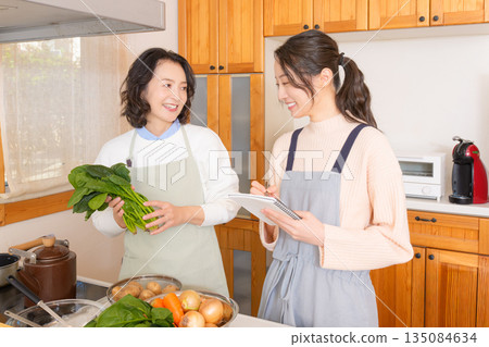Daughter learning cooking from mother Daughter learning cooking from mother 135084634