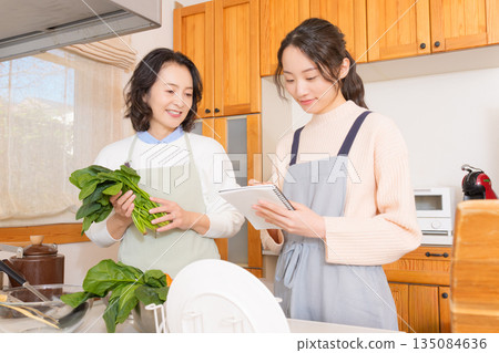 Daughter learning cooking from mother Daughter learning cooking from mother 135084636