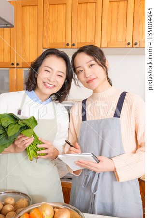 Daughter learning cooking from mother Daughter learning cooking from mother 135084645