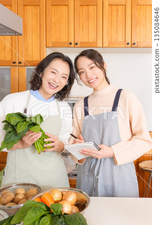 Daughter learning cooking from mother Daughter learning cooking from mother 135084646