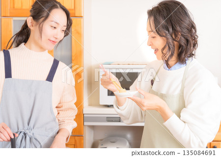 A mother tastes her daughter's meat and potato stew. A mother tastes her daughter's meat and potato stew. 135084691
