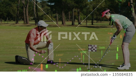 Golfing partners kneeling marking balls and lining putts on green, with checkered flag and overlays Golfing partners kneeling marking balls and lining putts on green, with checkered flag and overlays 135084835
