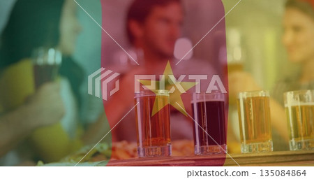 Friends toasting with four beer glasses on paddle in pub under Cameroon flag, with pizza dish Friends toasting with four beer glasses on paddle in pub under Cameroon flag, with pizza dish 135084864