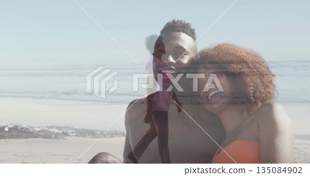 Smiling couple in swimwear leaning close and ghostly woman walking shore at beach, double exposure 135084902