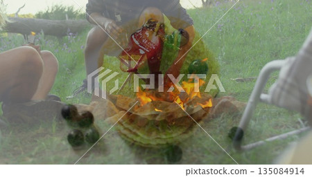 Gathering around fire pit, three campers sitting at clearing with red stool, cooler, mobility frame Gathering around fire pit, three campers sitting at clearing with red stool, cooler, mobility frame 135084914