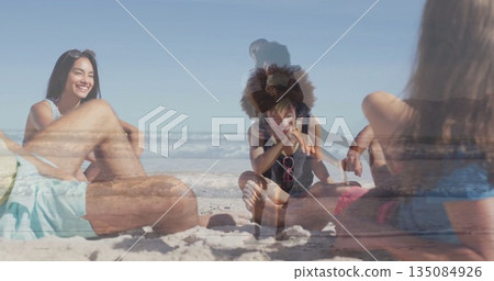 Relaxing group of adults and girl sitting on sandy shoreline, with pink sunglasses and beach towel Relaxing group of adults and girl sitting on sandy shoreline, with pink sunglasses and beach towel 135084926