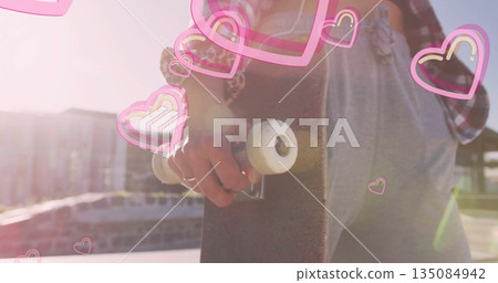 Holding skateboard by deck woman wearing red shirt with bracelets at skate park, heart overlay 135084942