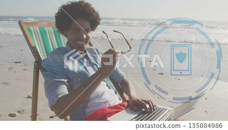 Reclining man in striped beach chair with sunglasses typing on laptop, security overlay, copy space Reclining man in striped beach chair with sunglasses typing on laptop, security overlay, copy space 135084986