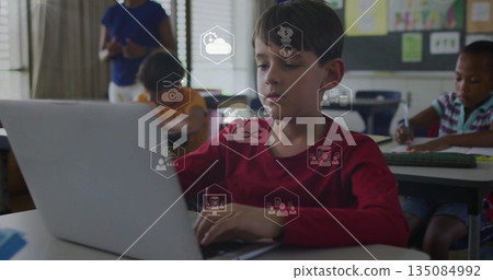 Typing boy wearing red shirt working on silver laptop at classroom desk, with teacher guiding Typing boy wearing red shirt working on silver laptop at classroom desk, with teacher guiding 135084992