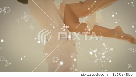 Lifting white clad couple dancing under pale sky outdoors with glowing molecular network overlays 135084996