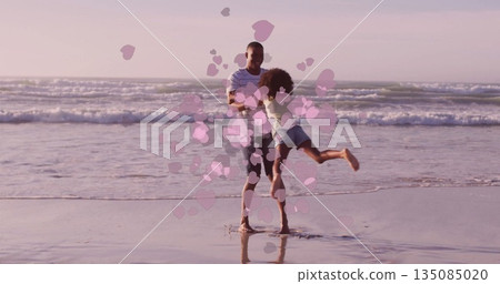 Spinning father with daughter in denim shorts on beach at sunset, transparent pink heart shapes Spinning father with daughter in denim shorts on beach at sunset, transparent pink heart shapes 135085020