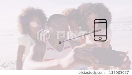 Family of four taking selfie on sandy shoreline at water's edge, with smartphone lens flare 135085027
