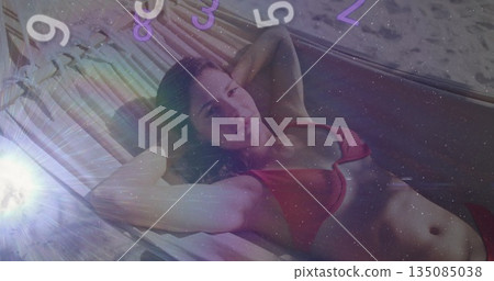 Reclining woman in red two-piece swimsuit relaxing on woven porch hammock, with floating numbers Reclining woman in red two-piece swimsuit relaxing on woven porch hammock, with floating numbers 135085038