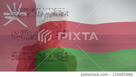 Standing woman wearing sleeveless green top on beach with waves, national flag overlay, code matrix 135085066