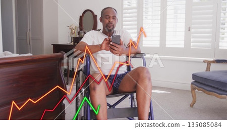Senior man sitting in wheelchair and using smartphone in bedroom, viewing colored line graphs 135085084