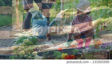 Watering father and daughter tending seedlings in backyard raised garden bed with blue watering can Watering father and daughter tending seedlings in backyard raised garden bed with blue watering can 135085090