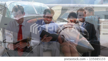 Reviewing papers business team collaborating on tarmac next to propeller airplane, with open hatch 135085133