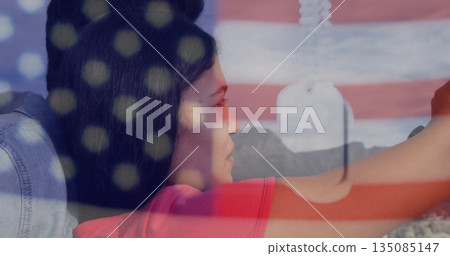 Standing couple wearing red t shirt, denim jacket overlooking mountains, with dog tags flag overlay 135085147