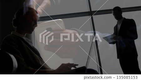Typing businesswoman on laptop in lobby by grid windows with tablet, smartphone copy space Typing businesswoman on laptop in lobby by grid windows with tablet, smartphone copy space 135085153