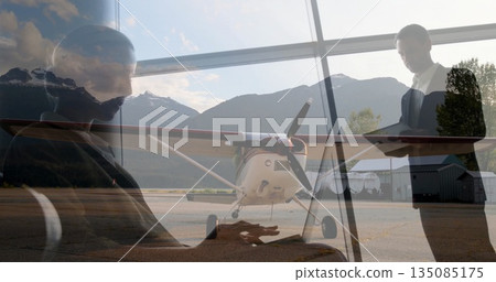 Merging lounge and runway, showing colleagues working with laptop, tablet and propeller airplane 135085175
