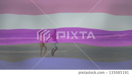 Walking couple wearing swimwear and holding hands along sandy beach water's edge, with ocean waves Walking couple wearing swimwear and holding hands along sandy beach water's edge, with ocean waves 135085191
