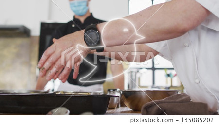 Sprinkling seasoning with chef's hands over metal trays in commercial kitchen, with smartwatch Sprinkling seasoning with chef's hands over metal trays in commercial kitchen, with smartwatch 135085202