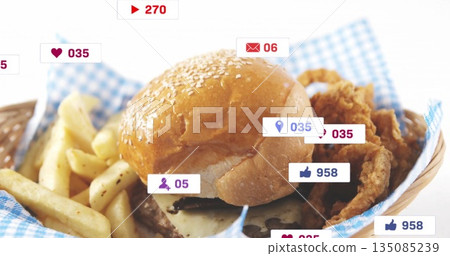 Sesame burger bun resting atop patty with melted cheese in basket on table, fries, chicken, icons 135085239