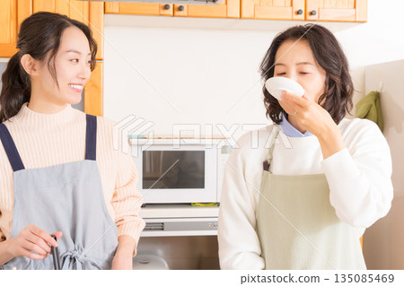 一位母親品嚐女兒做的肉和馬鈴薯燉菜。 一位母親品嚐女兒做的肉和馬鈴薯燉菜。 135085469
