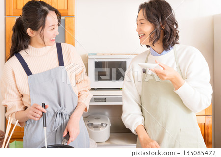 A mother tastes her daughter's meat and potato stew. 135085472