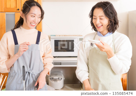 一位母親品嚐女兒做的肉和馬鈴薯燉菜。 一位母親品嚐女兒做的肉和馬鈴薯燉菜。 135085474