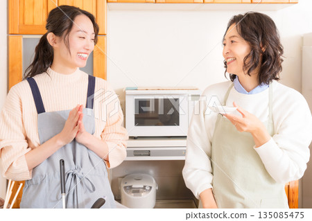 A mother tastes her daughter's meat and potato stew. A mother tastes her daughter's meat and potato stew. 135085475
