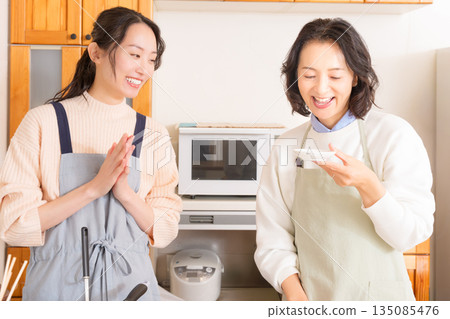 一位母親品嚐女兒做的肉和馬鈴薯燉菜。 一位母親品嚐女兒做的肉和馬鈴薯燉菜。 135085476