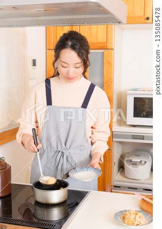 A young woman serving meat and potatoes on a plate A young woman serving meat and potatoes on a plate 135085478