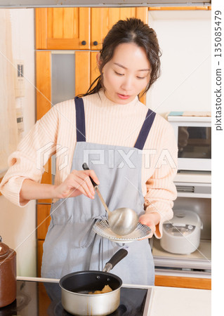 一位年輕女子將肉和馬鈴薯盛在盤子裡。 135085479
