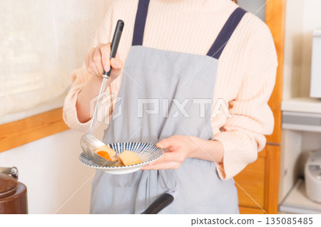 A young woman serving meat and potatoes on a plate 135085485