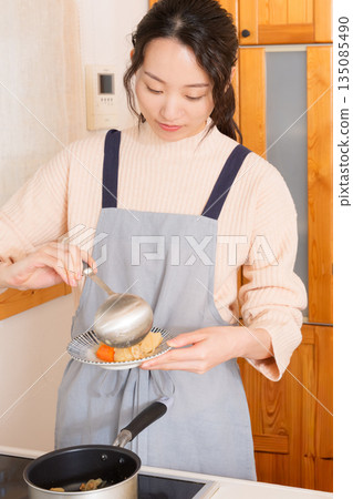 A young woman serving meat and potatoes on a plate A young woman serving meat and potatoes on a plate 135085490