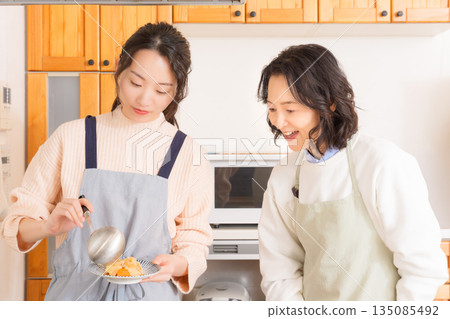 A mother tastes her daughter's meat and potato stew. A mother tastes her daughter's meat and potato stew. 135085492