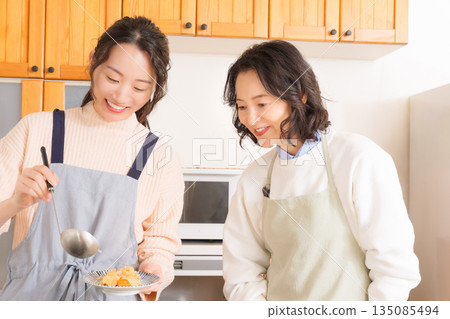 A mother tastes her daughter's meat and potato stew. A mother tastes her daughter's meat and potato stew. 135085494