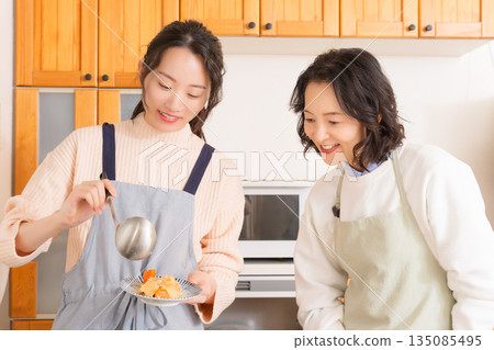 A mother tastes her daughter's meat and potato stew. A mother tastes her daughter's meat and potato stew. 135085495