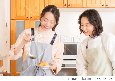 A mother tastes her daughter's meat and potato stew. A mother tastes her daughter's meat and potato stew. 135085496