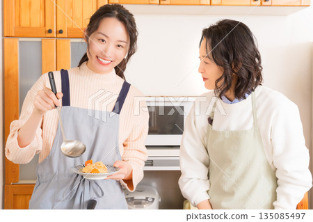 A mother tastes her daughter's meat and potato stew. A mother tastes her daughter's meat and potato stew. 135085497