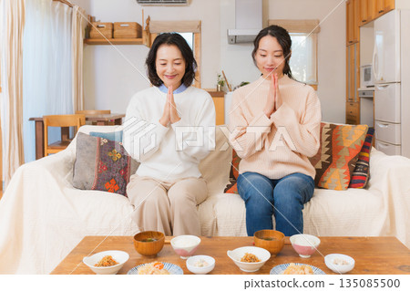 Mother and daughter eating together with hands together 135085500