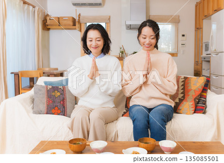 Mother and daughter eating together with hands together 135085501